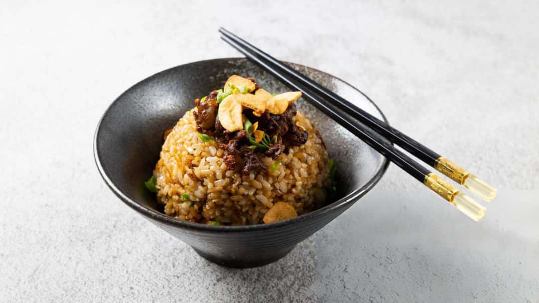 A bowl of black garlic and shiitake fried rice in a bowl.
