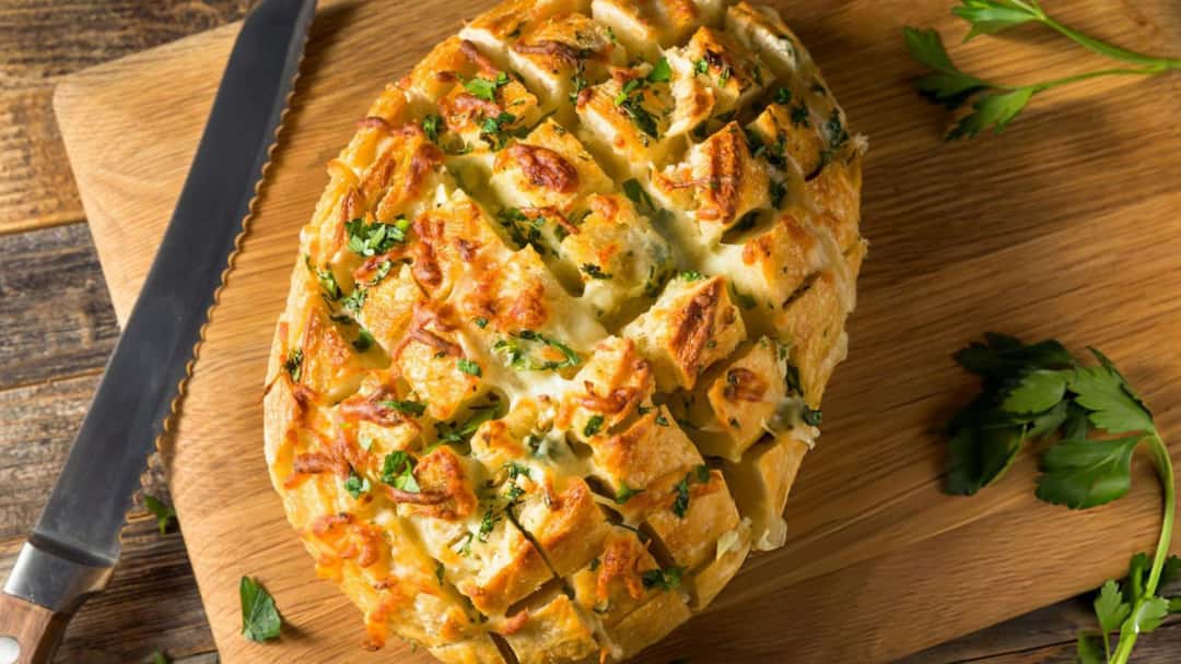 Cheesy garlic pull-apart bread with melted cheese oozing on a wooden board
