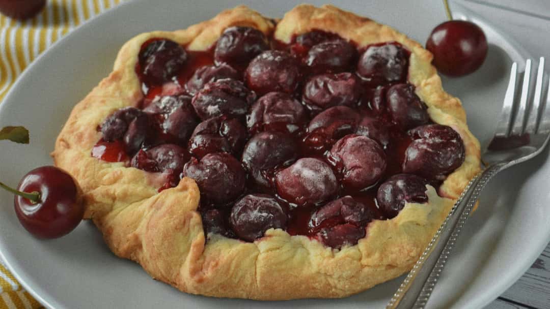 Top view of cherry galette on a plate. (banner image)