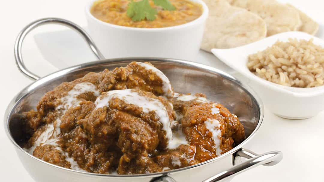 Traditional Goan chicken xacuti curry in a kadhai with sides