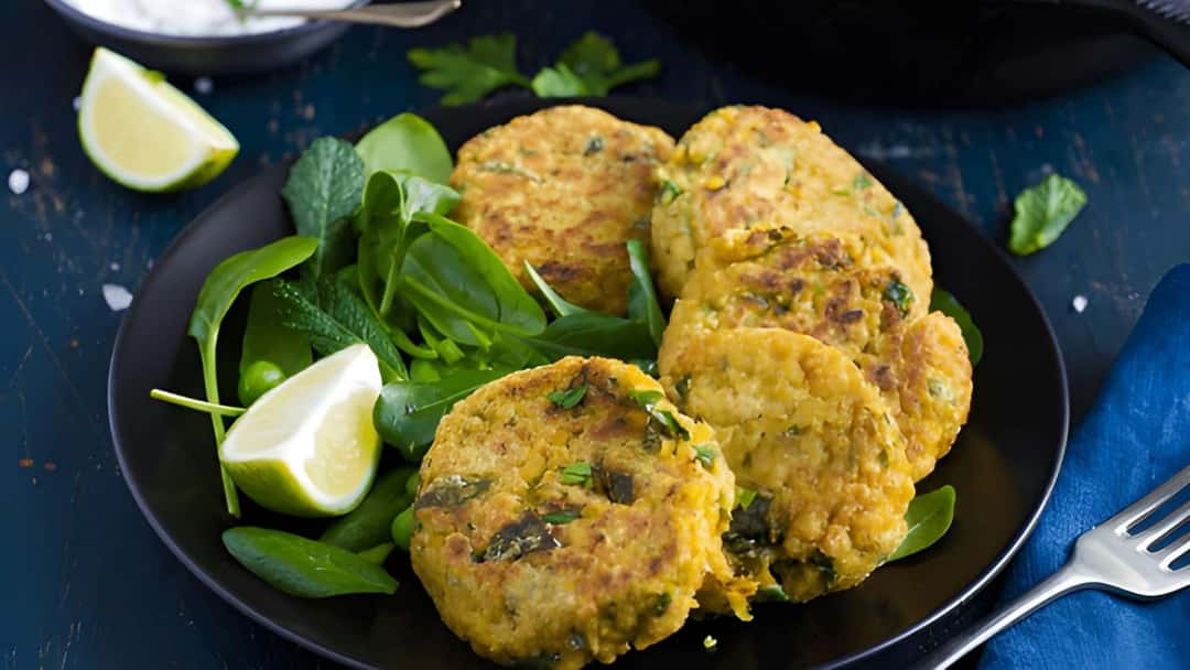 Chickpea and spinach fritters stacked on a black plate