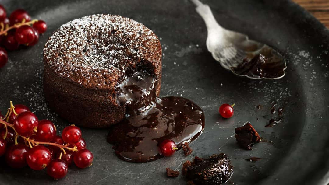  Individual chocolate lava cake with molten chocolate flowing from the centre onto a plate. (banner image)