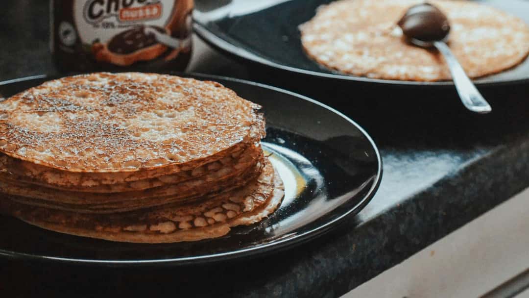  Stack of French crepes on a plate with spread. (banner image)