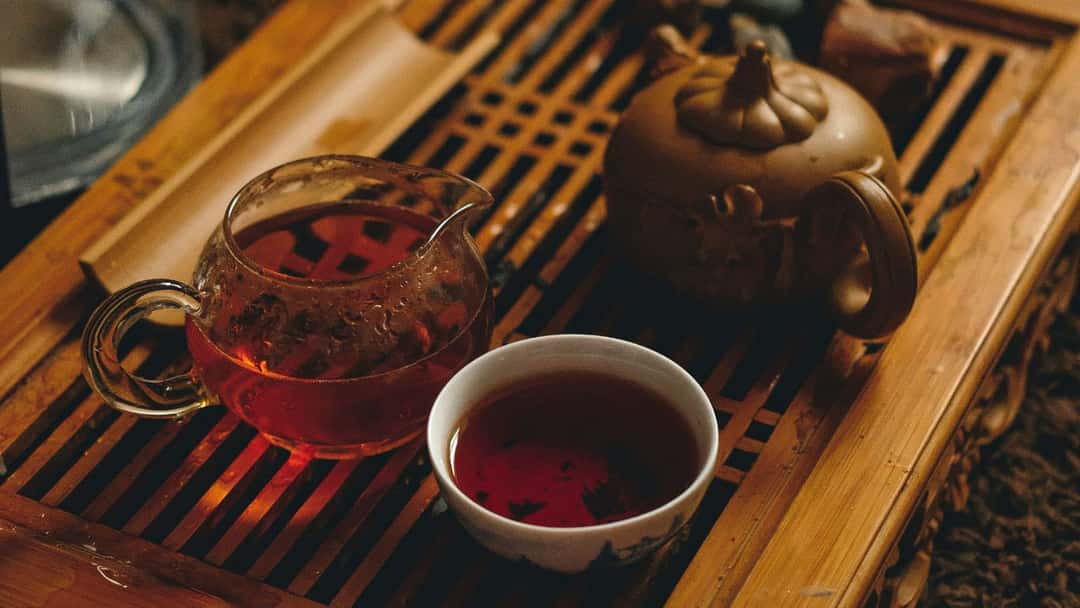 Tea leaves being put inside a teapot.