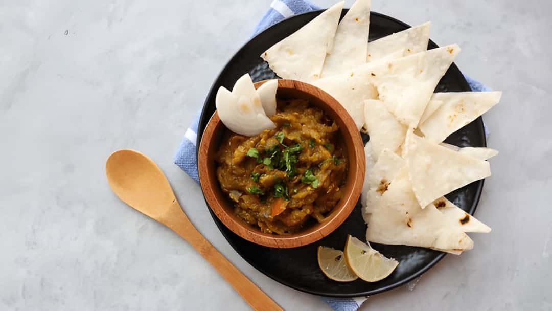 Jowar bhakri with a bowl of baingan bharta on a plate