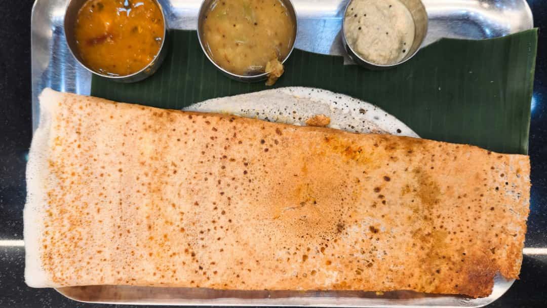 Godhuma Dosa in a banana leaf place on a steel plate with sambar and chutneys