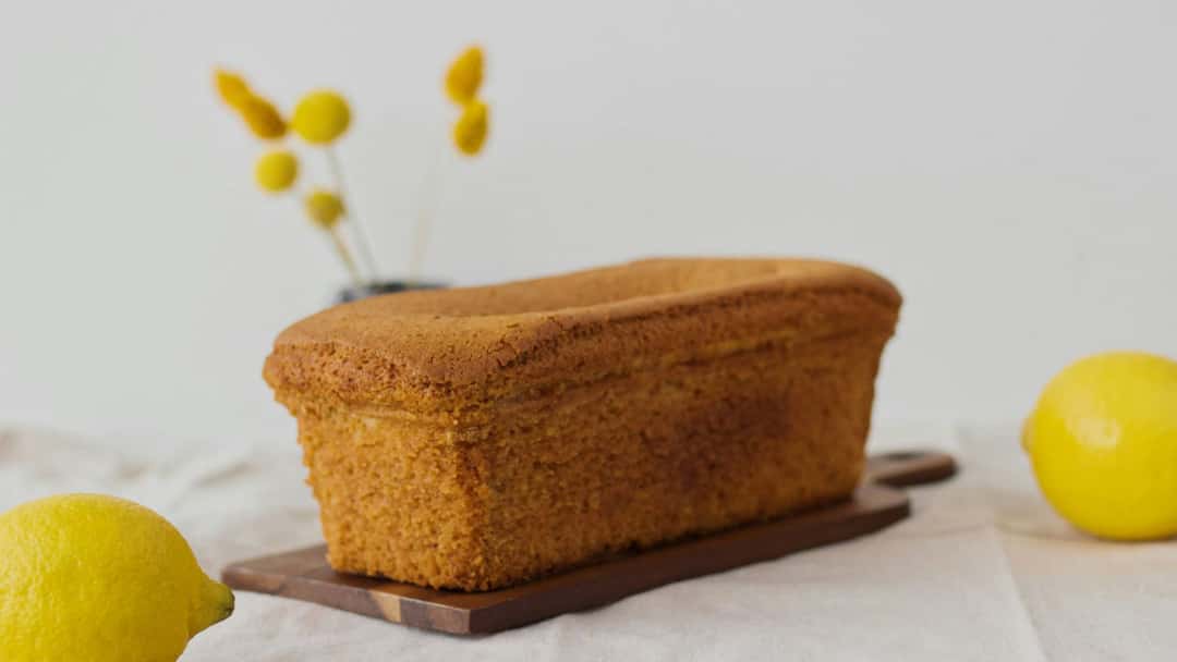 A loaf of lemon cake on a wooden board. (banner image)