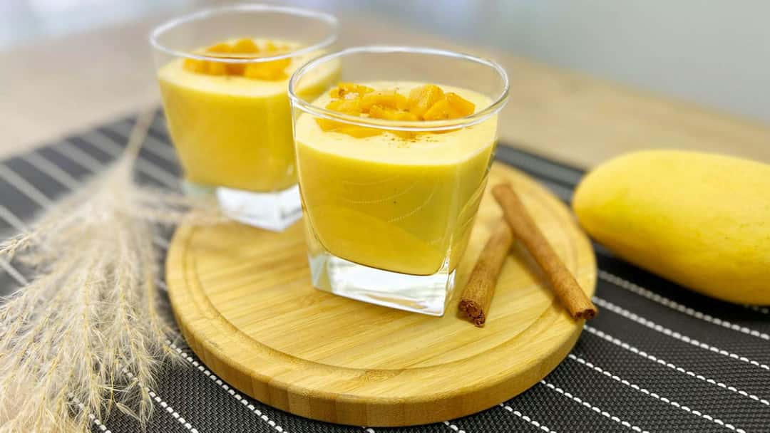 Glasses of coconut mango lassi on a wooden board