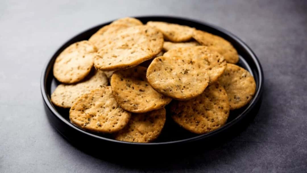 Crispy methi mathris stacked on a plate.