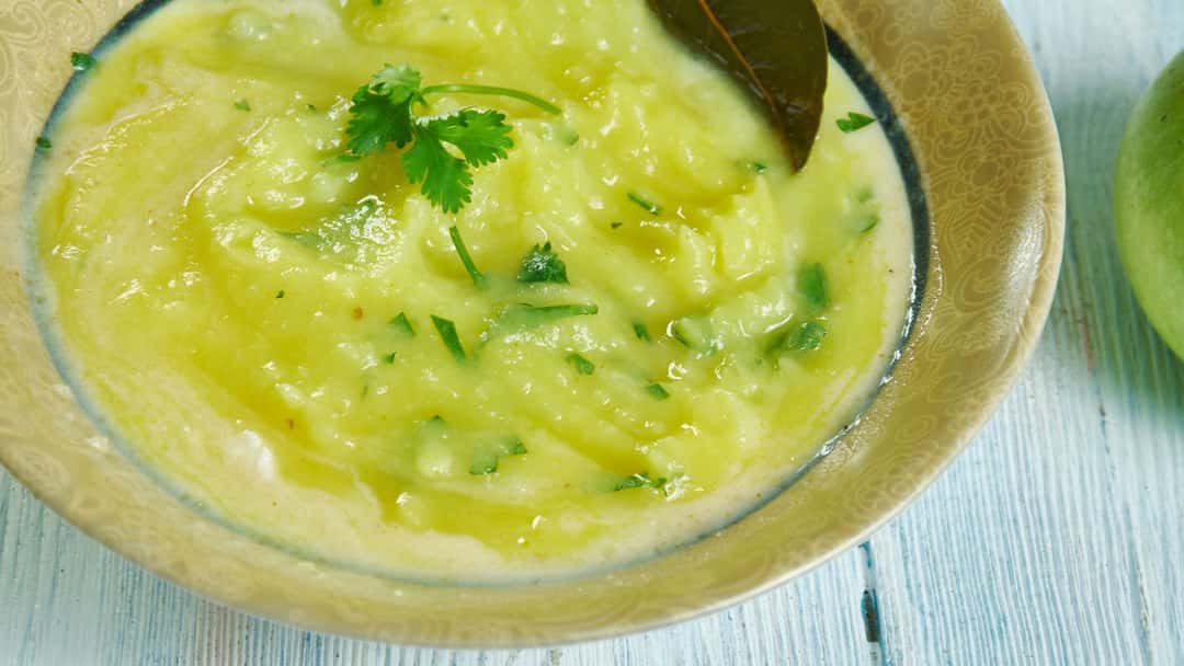 Top view of raw mango pithla in a bowl. (banner image)