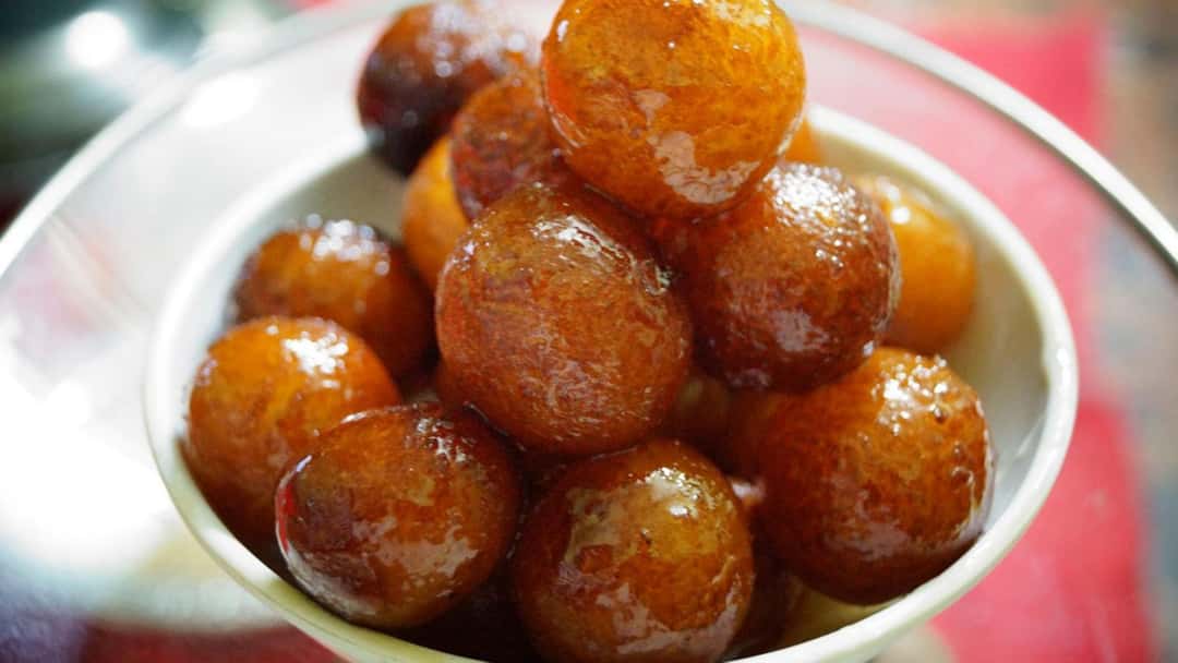 Pile of gulab jamun doughnut holes in a bowl