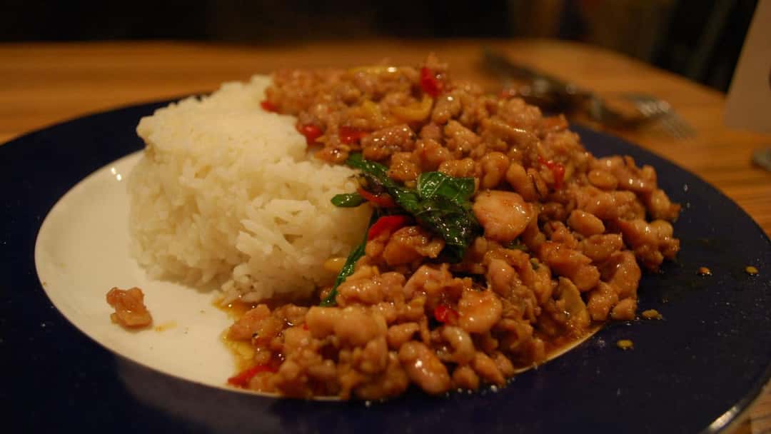 Thai basil chicken on a plate with steamed rice