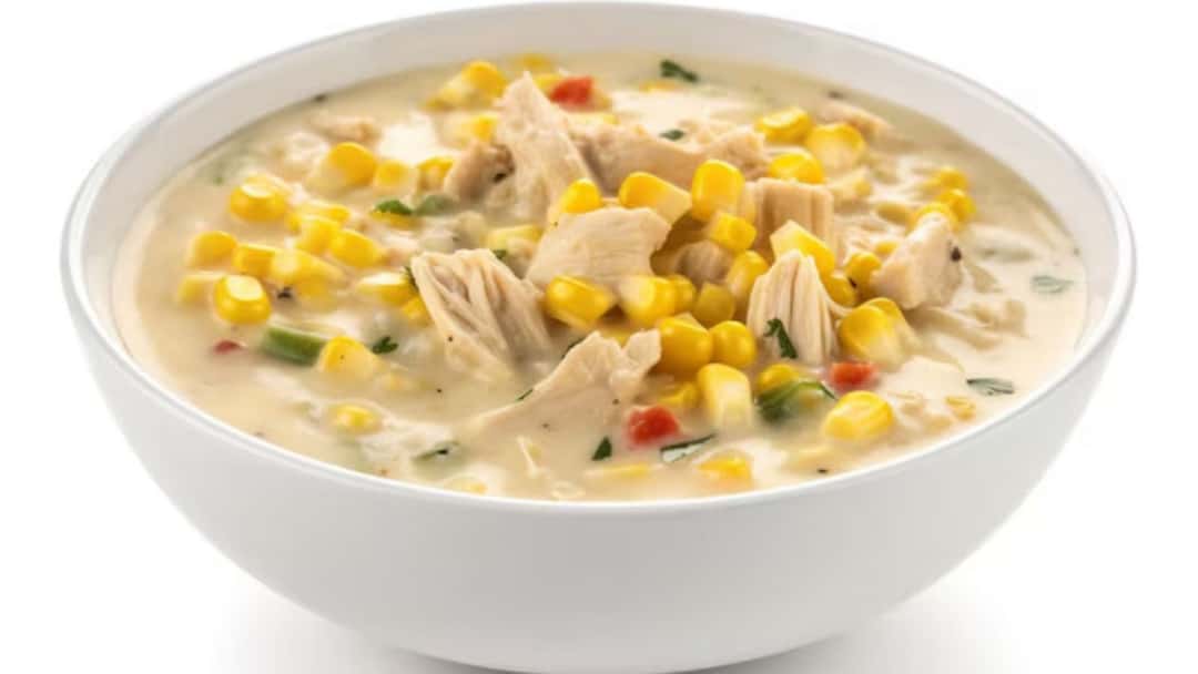 Chicken sweet corn soup with shredded chicken, sweet corn and spring onions in a bowl
