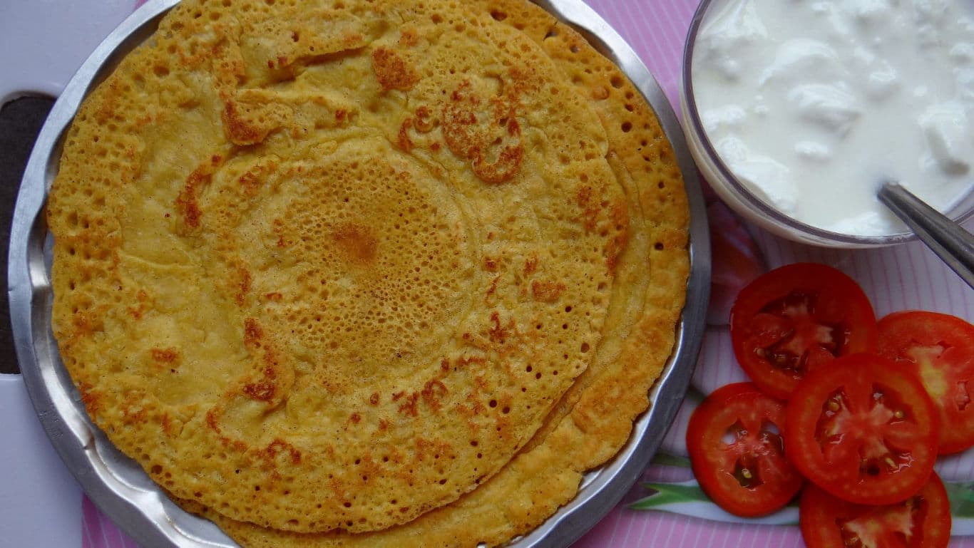 Indian besan chilla served with yogurt and tomatoes