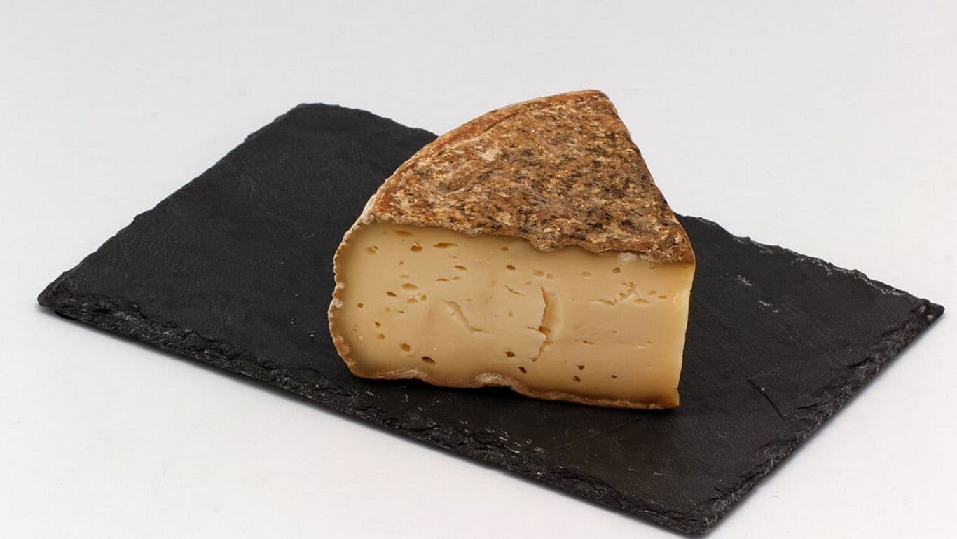 Wedge of aged cheese on slate serving board