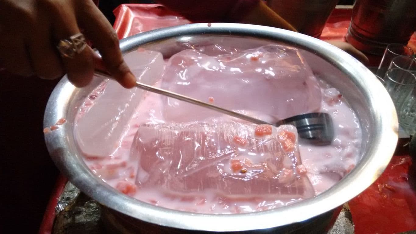 Large bowl of chilled rose milk with ice blocks