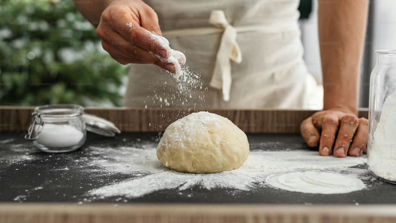 Baker Sprinkling Flour Over Fresh Dough Ball