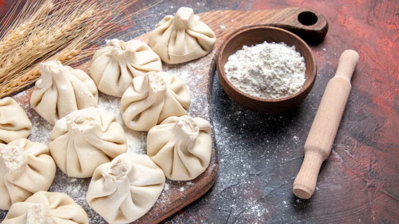 Raw dumplings with flour on rustic wooden board