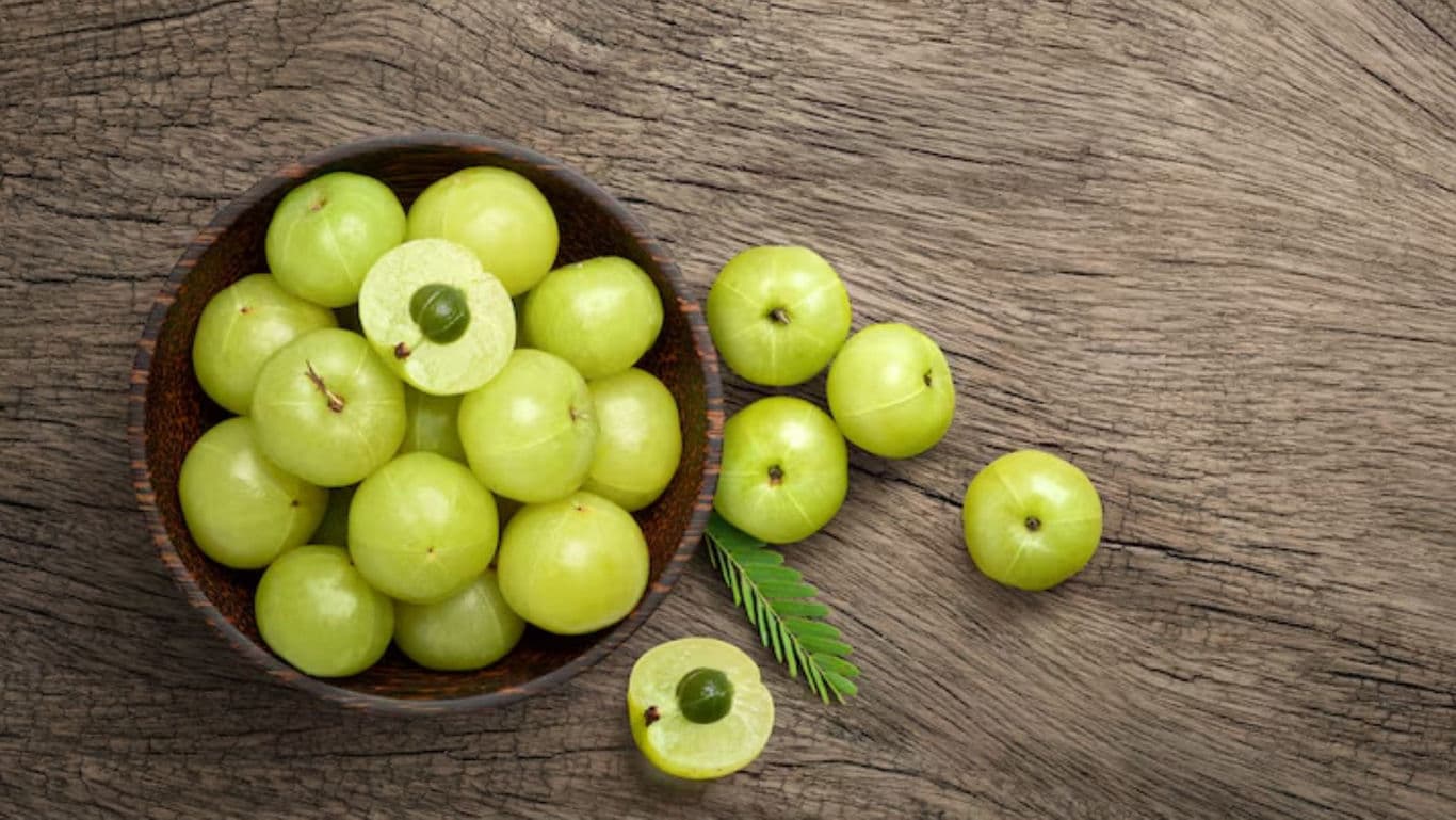 Fresh Indian gooseberries in wooden bowl on table
