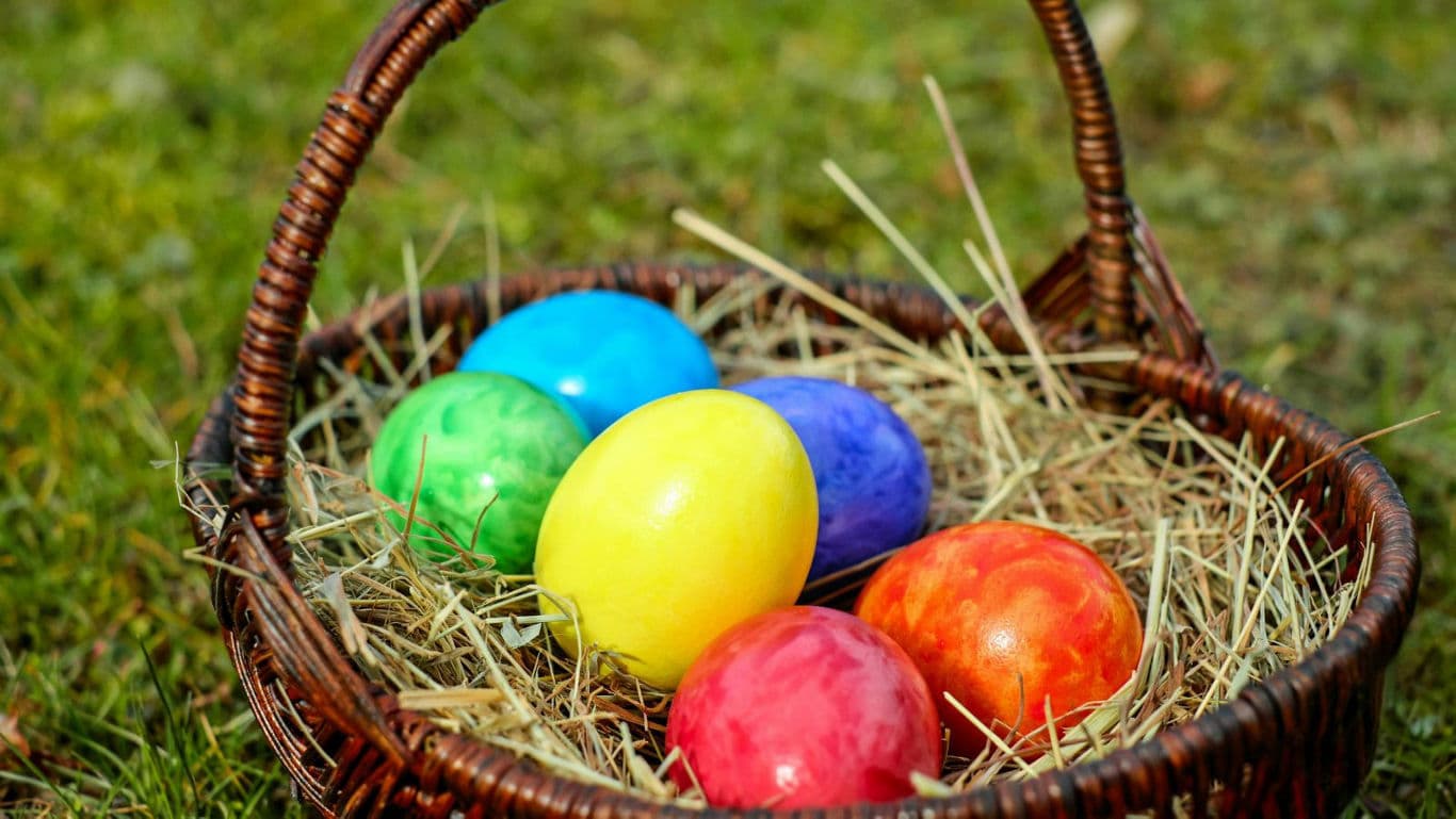Colorful Easter Eggs in Wicker Basket Outdoors