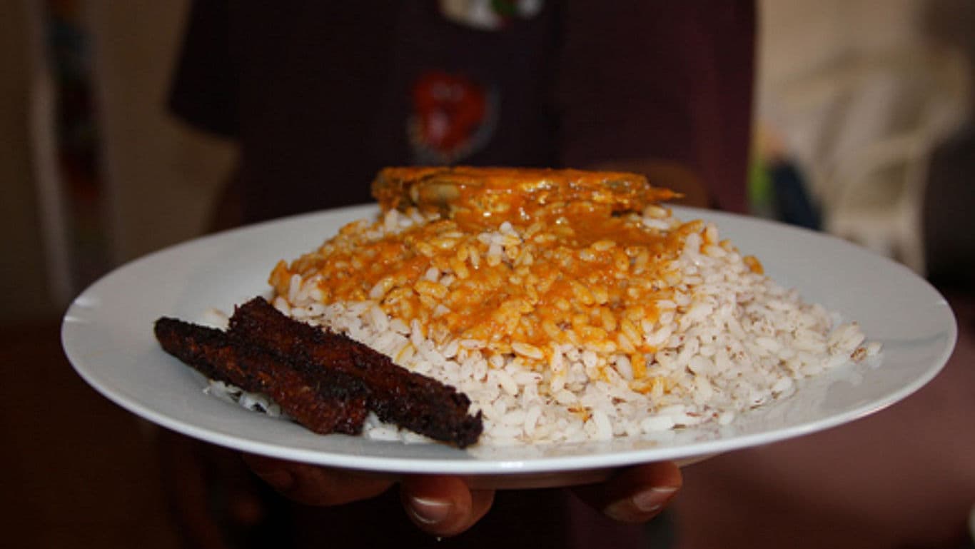 Plate of rice with sauce and fried plantain