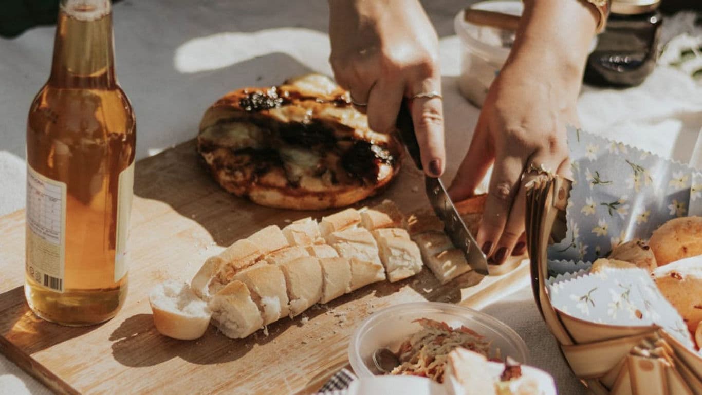 Outdoor picnic with bread, pizza, and bottled drink