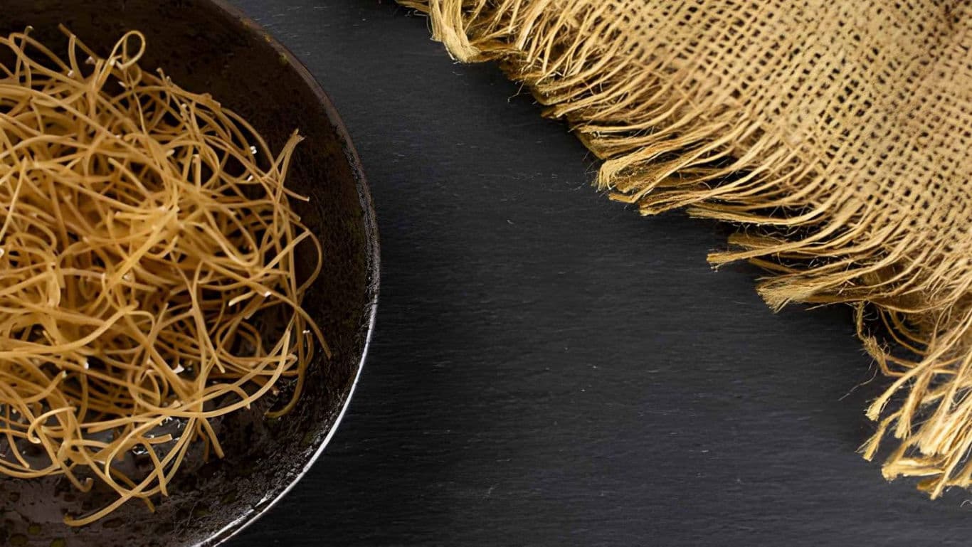Dry Thin Noodles in Dark Ceramic Bowl Over Slate