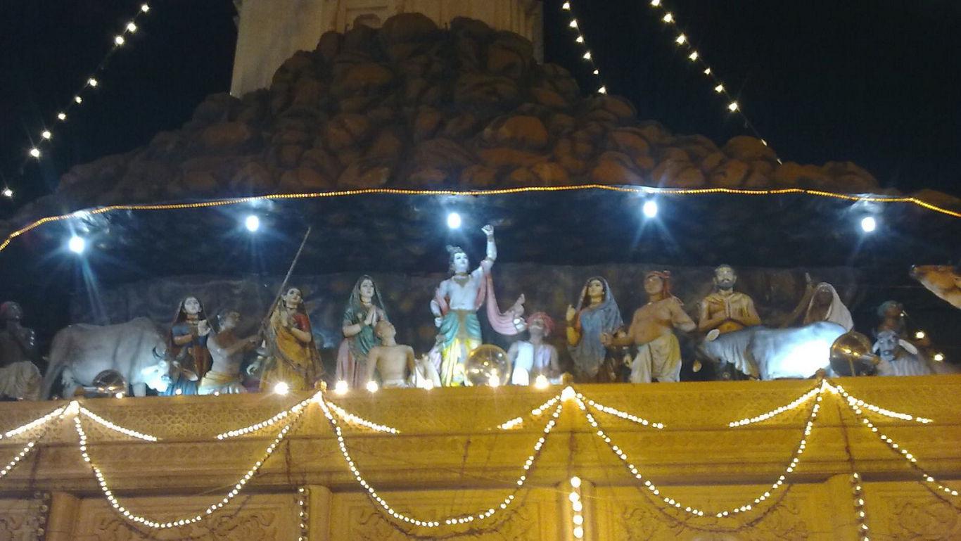Krishna statue with divine figures at night