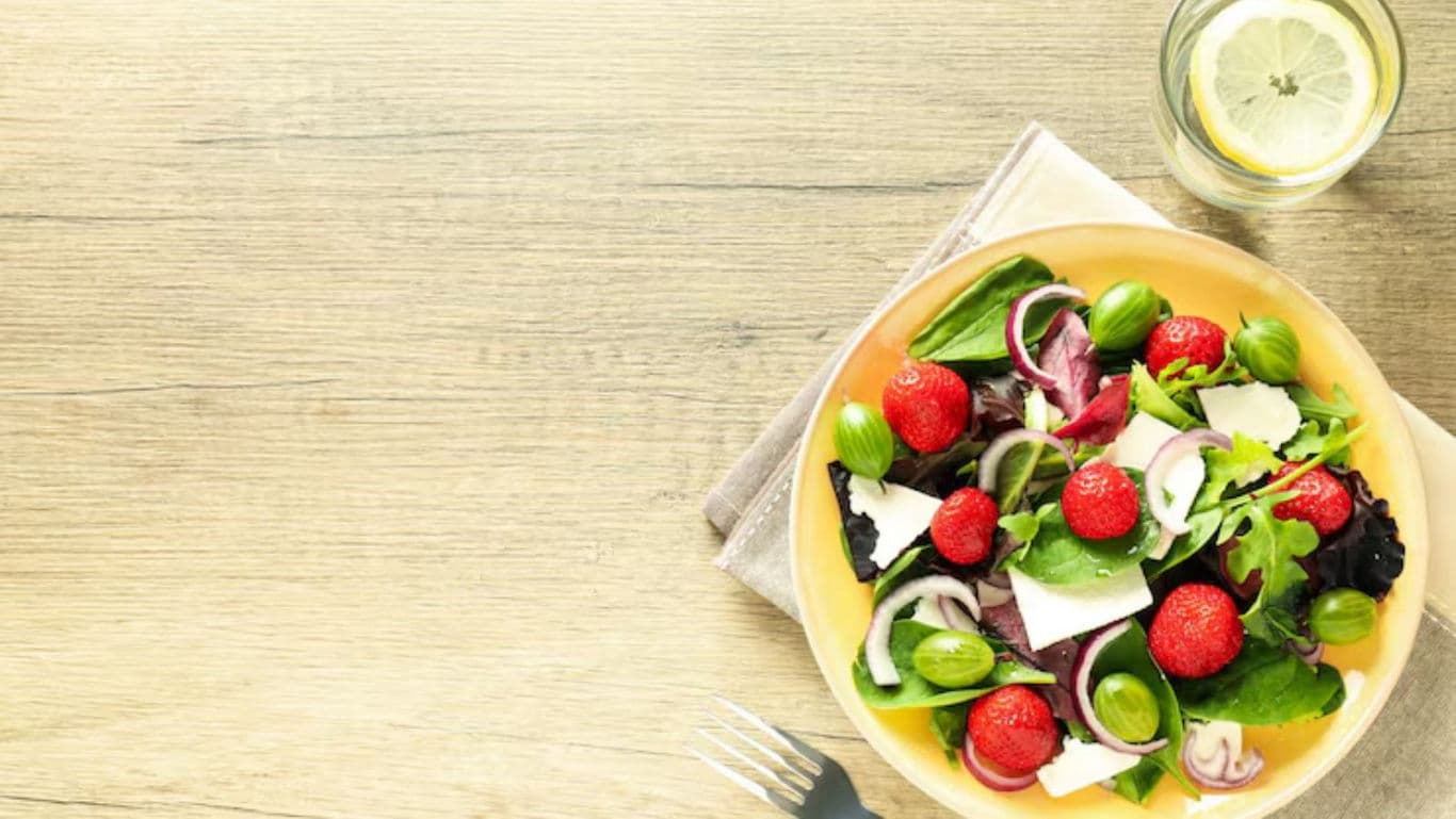Fresh strawberry green salad on wooden table
