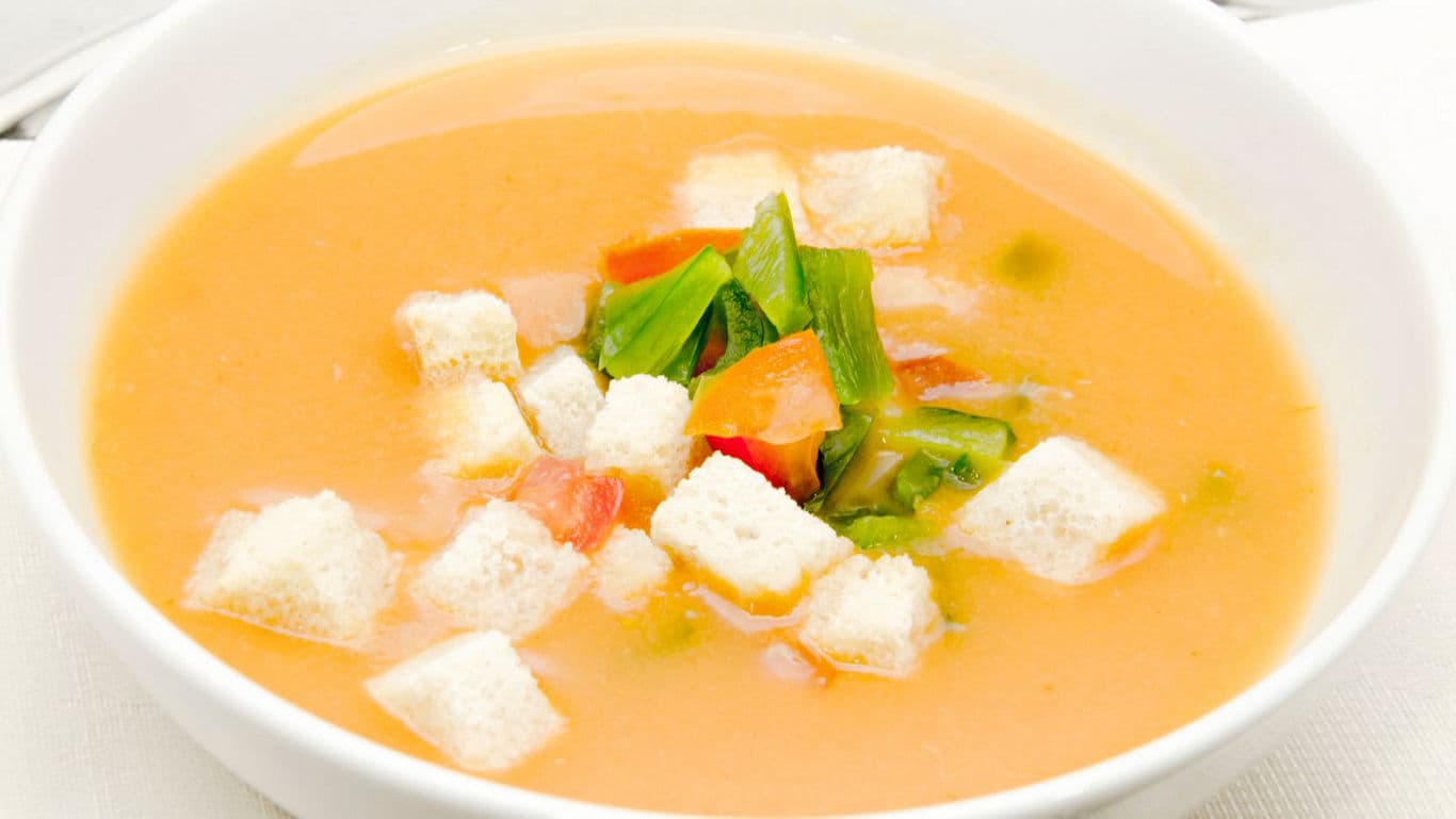 Creamy vegetable soup with croutons in white bowl
