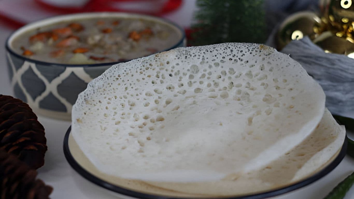 Traditional appam served with festive stew background