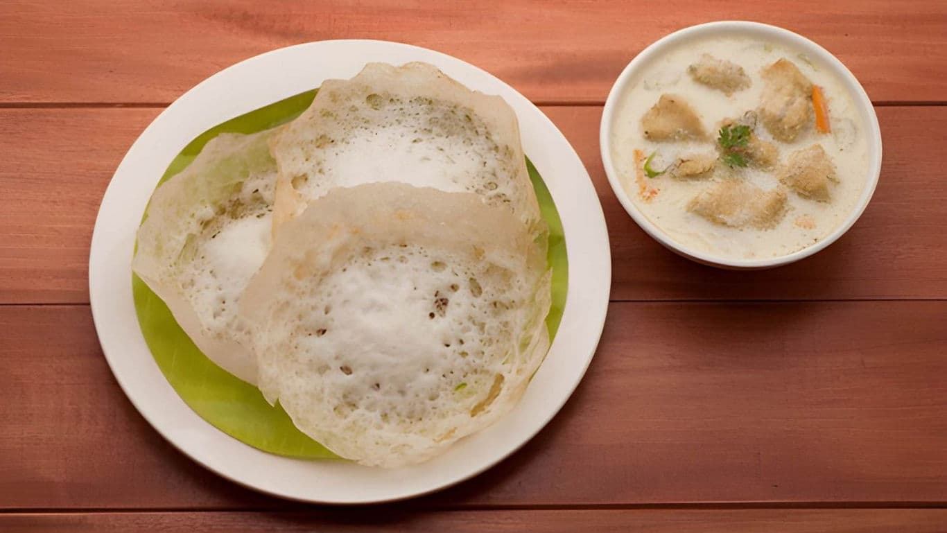 Appam with vegetable stew on wooden table
