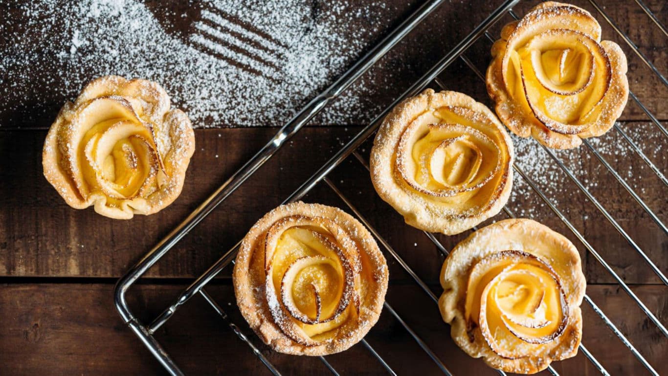 Apple rose pastries cooling on wire rack with powdered sugar