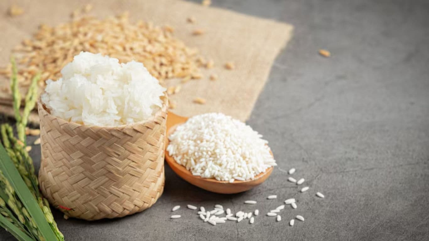Cooked white rice and raw grains on rustic surface