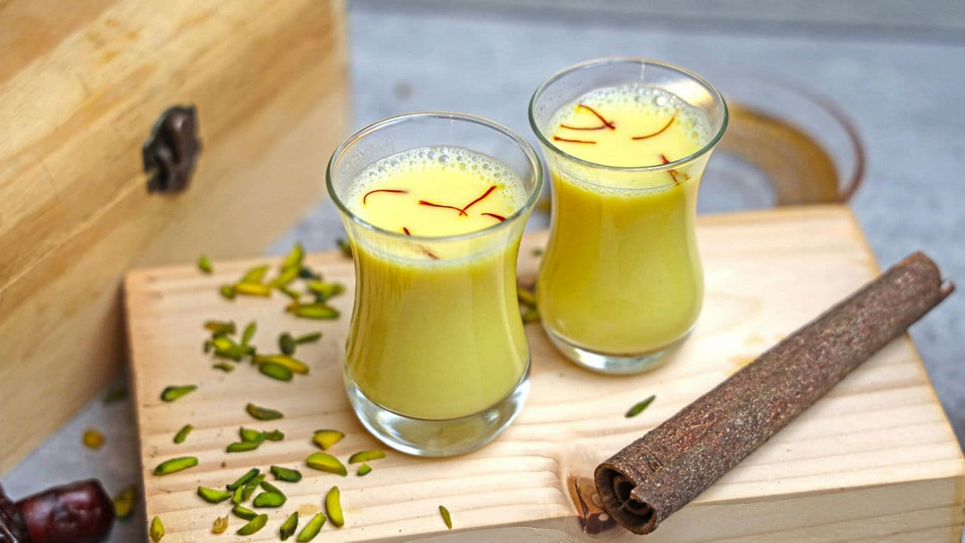 Two glasses of saffron milk with pistachios and cinnamon