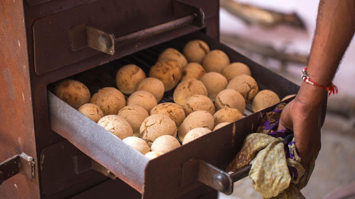 Baati being cooked in a traditional oven