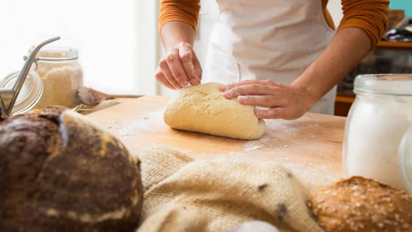 Person kneading dough in rustic kitchen setting