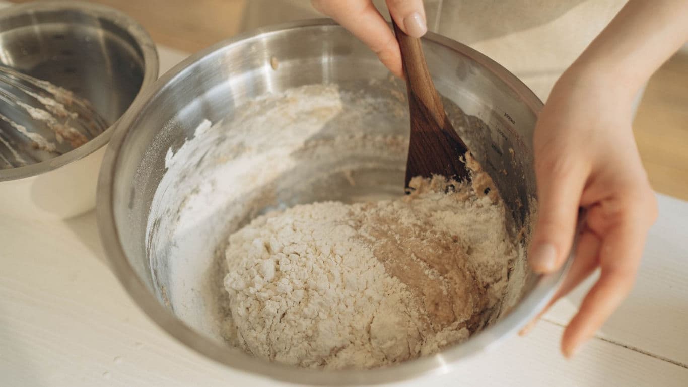 Person mixing dough in stainless steel bowl