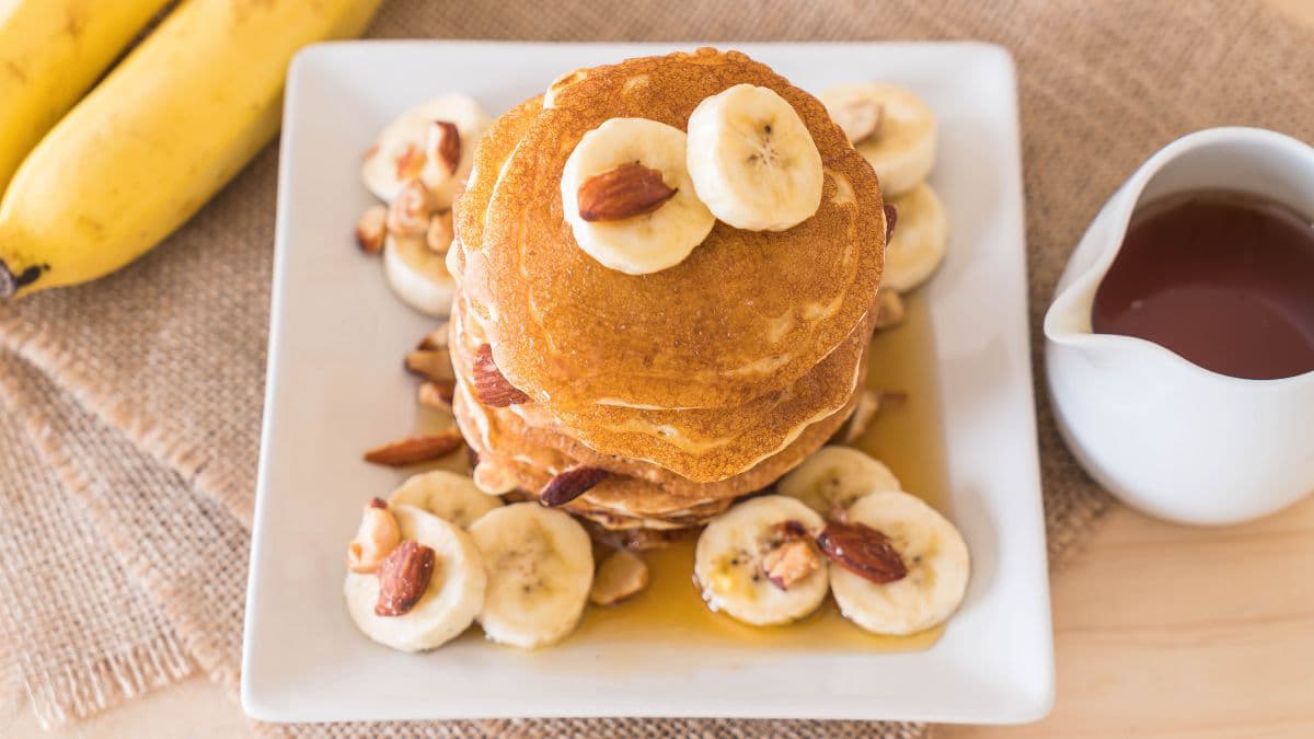 Pancakes with banana slices on top and syrup on the side