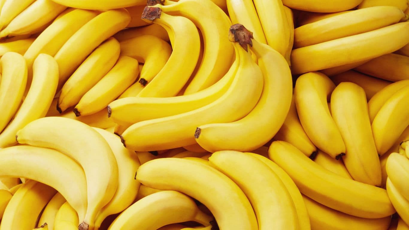 Fresh ripe bananas in a vibrant yellow pile