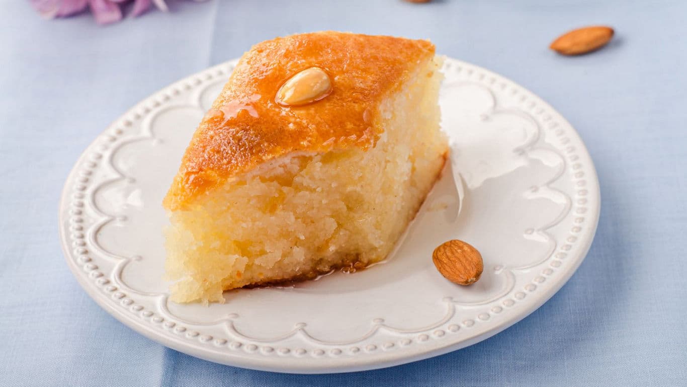 Moist almond-topped semolina cake slice on plate
