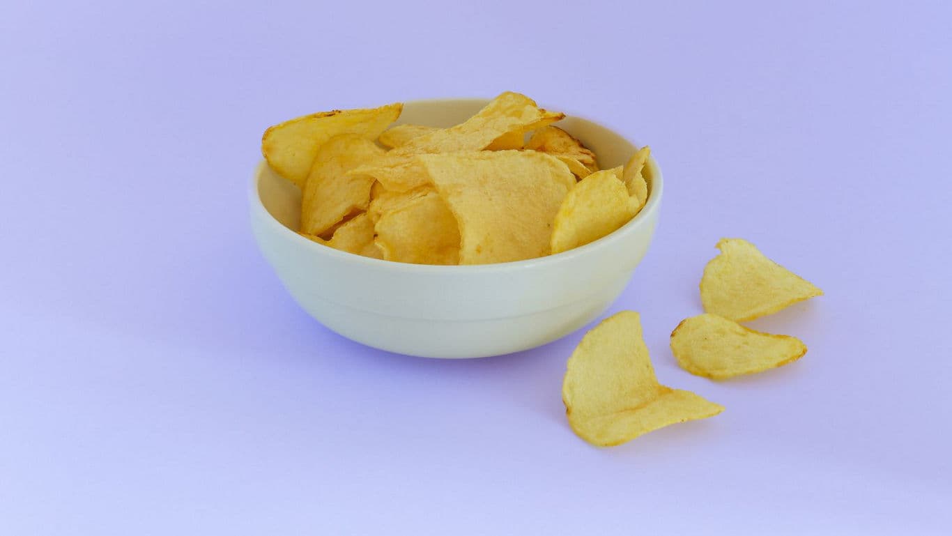 Bowl of potato chips on purple background