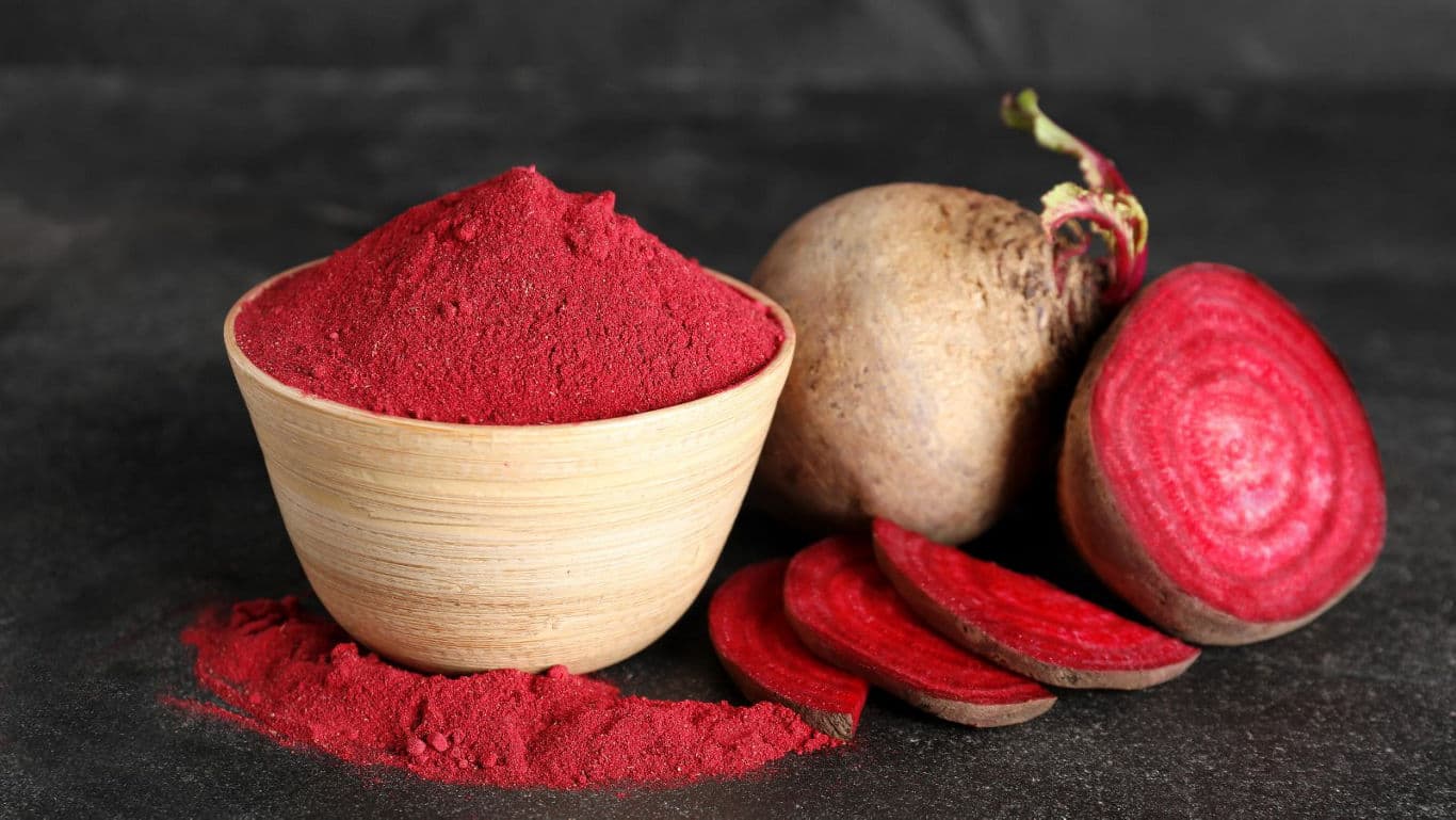 Wooden bowl of beetroot powder with fresh beets