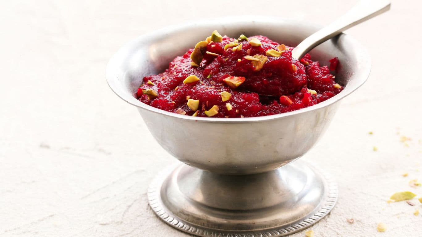 Silver bowl with red dessert and pistachio garnish