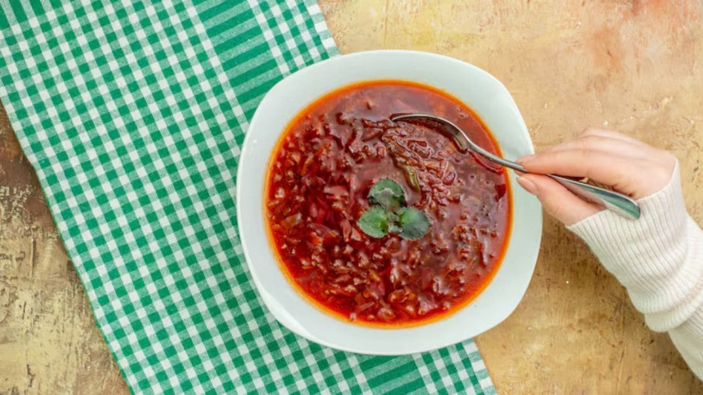 Bowl of red soup with fresh herbs and spoon