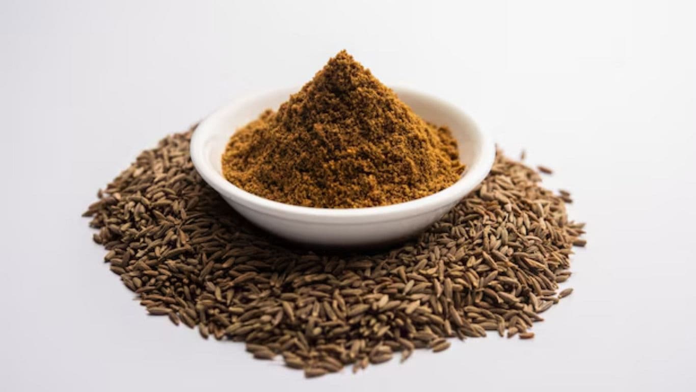Bowl of ground spice surrounded by whole seeds