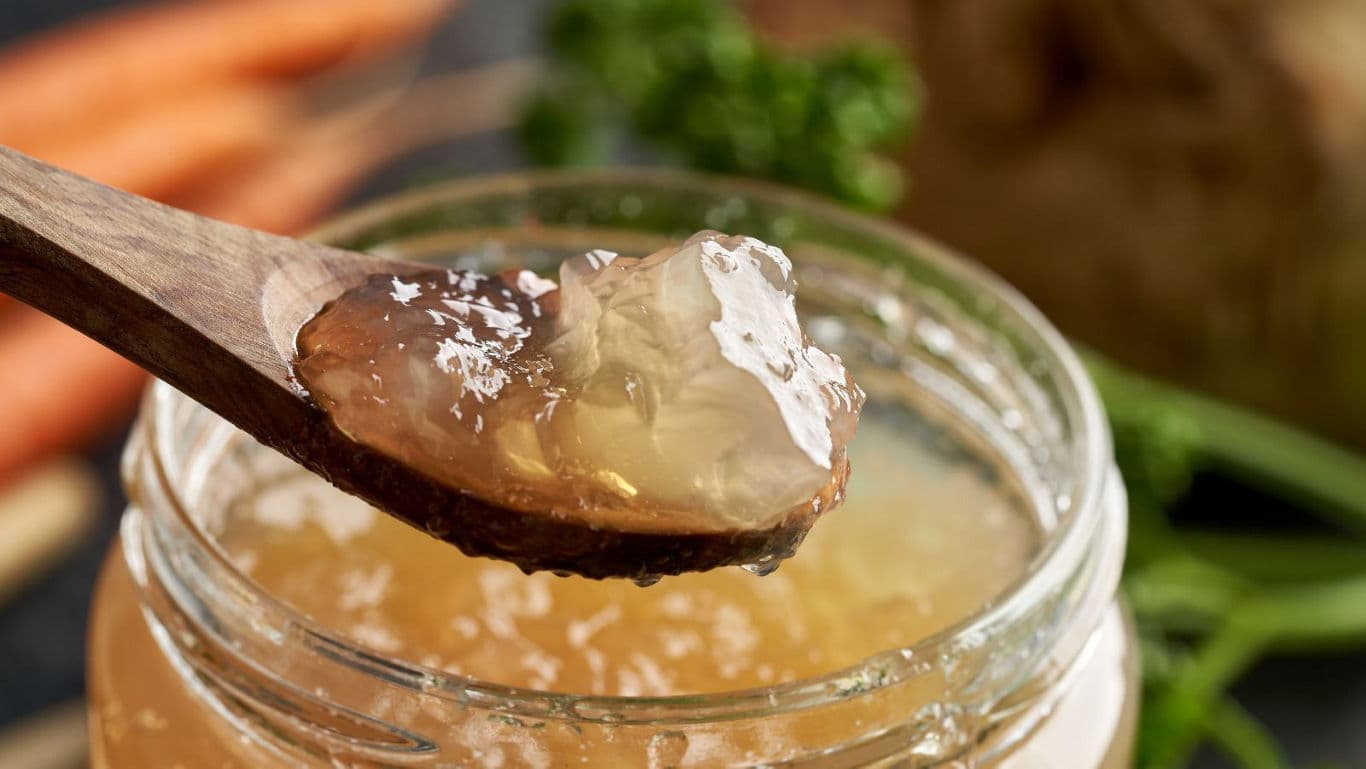 Wooden spoon scooping clear jelly from jar