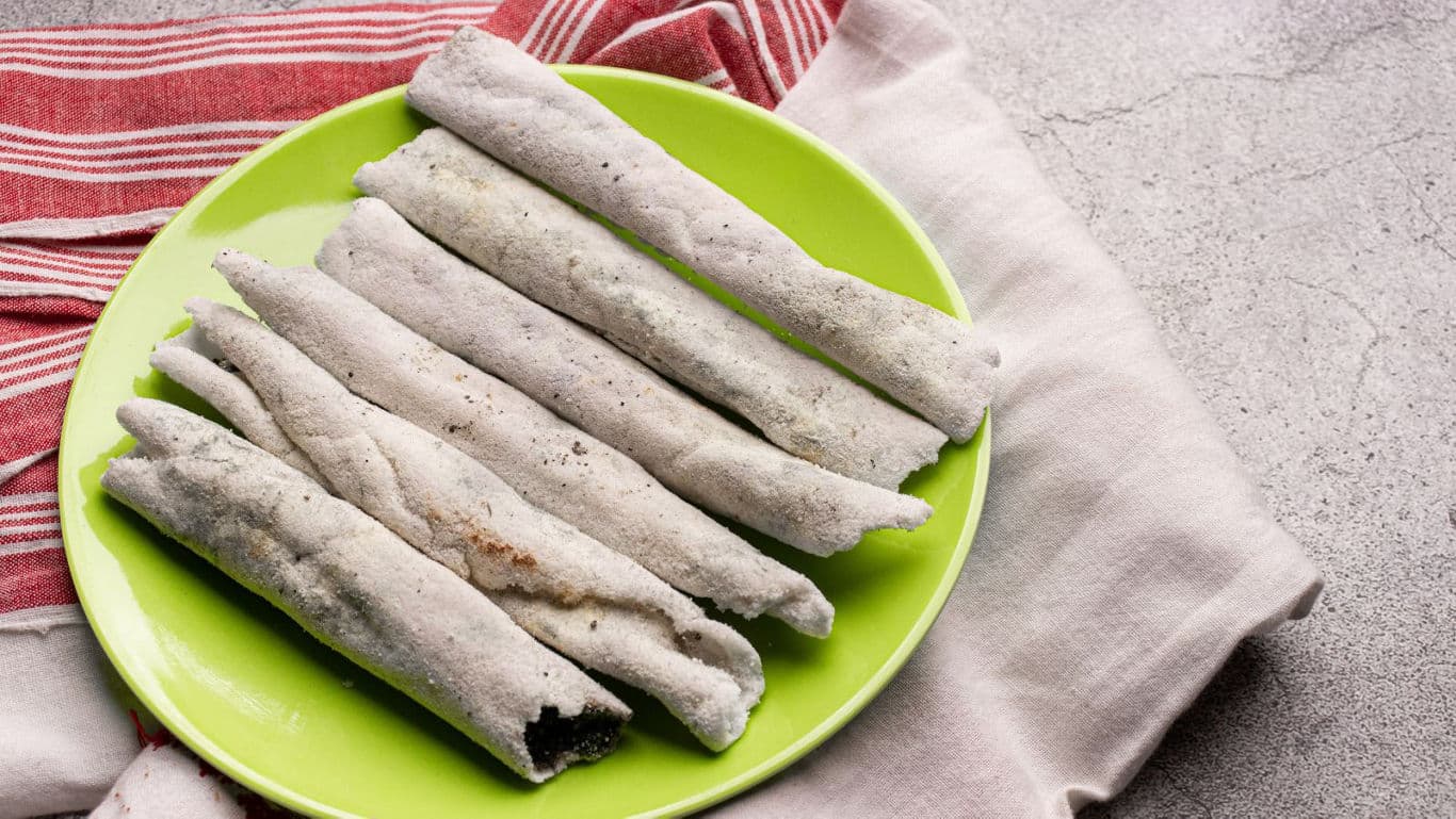 Traditional rolled Indian rice crepes on green plate