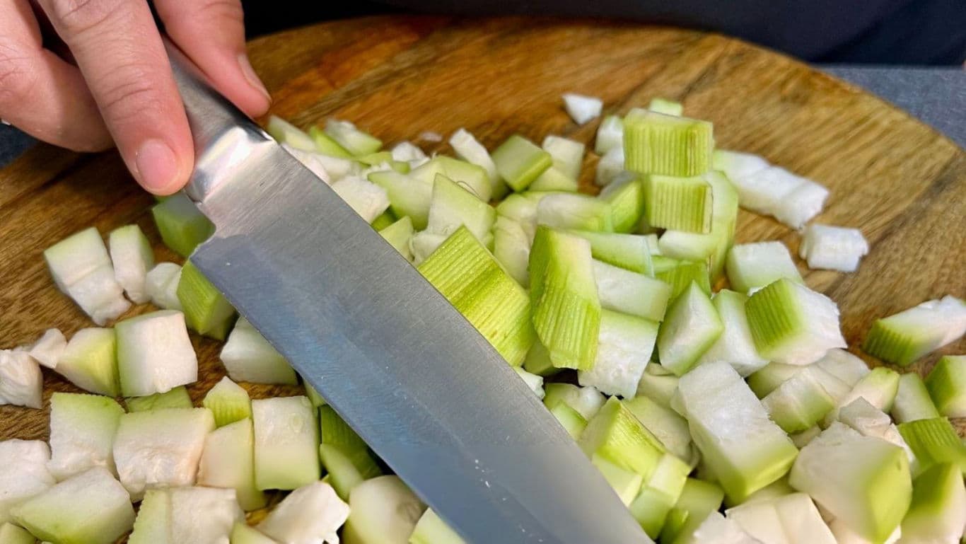 Close-up of knife chopping green vegetables