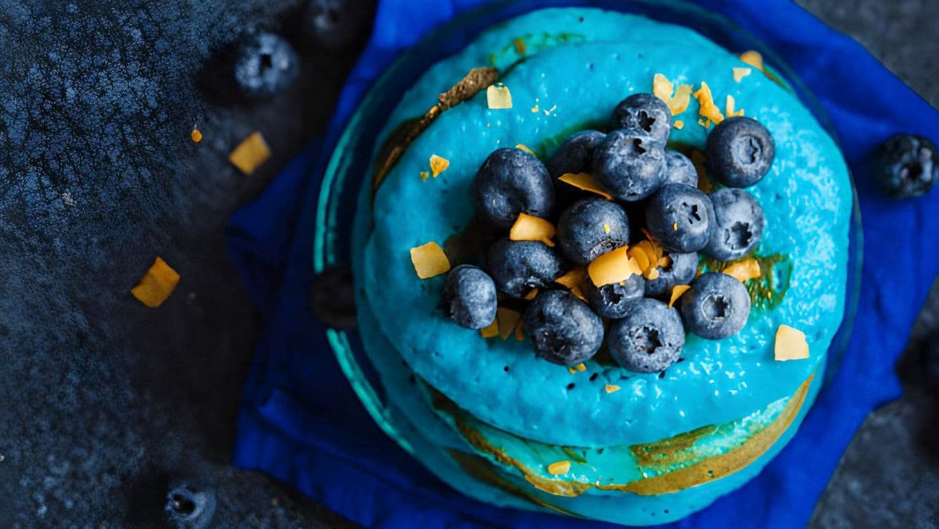 Blueberry cake with vibrant blue frosting and topping